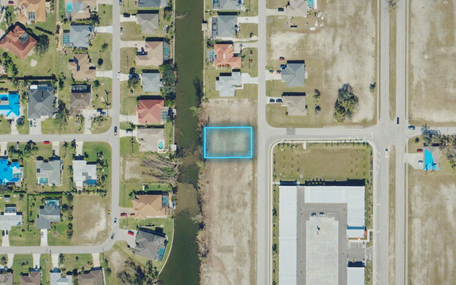 Aerial photo of a canal neighborhood in Cape Coral with one lot outlined in blue
